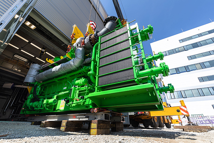 Ein großer, grüner Motor wird in eine Halle gehoben.