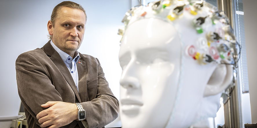 Smiling man behind a ceramic figure in the shape of a human head