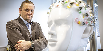 Smiling man behind a ceramic figure in the shape of a human head