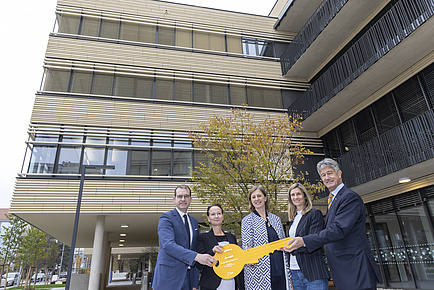 Group photo with three women and two men and an oversized symbolic key