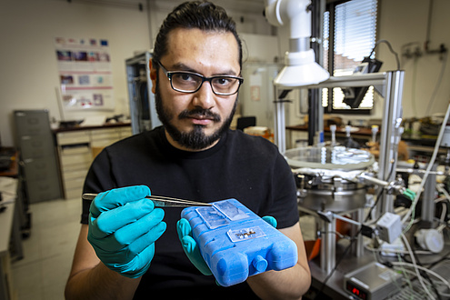 A man is holding a freezer element with frozen glass plates on it.