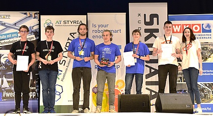 Seven people stand on a stage.