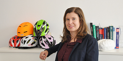 Corina Klug in her office. In the background: bicycle helmets and books.