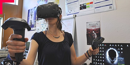 Woman with game console and data glasses at her computer workstation.