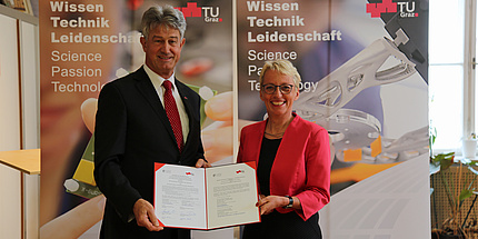 ein Mann und eine Frau halten ein Vertragsdokument in die Kamera