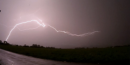 Lightning discharges from a cloudy sky and strikes an uninhabited area.