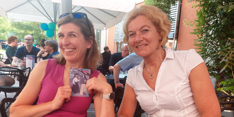 two women sitting next to each other and looking into the camera