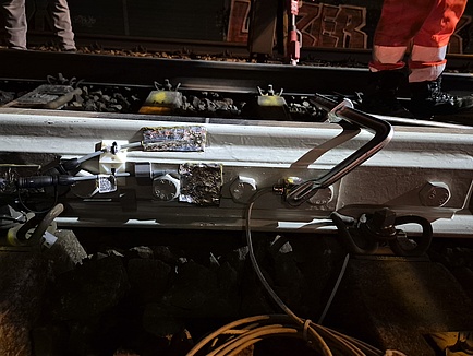 A section of railway track with bolts attached to its side for reinforcement. Sensors are attached to the track.