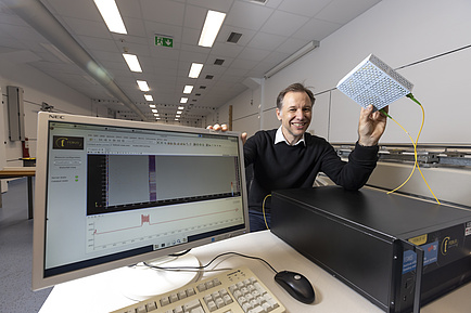 One person holding a small plastic box is smiling into the camera