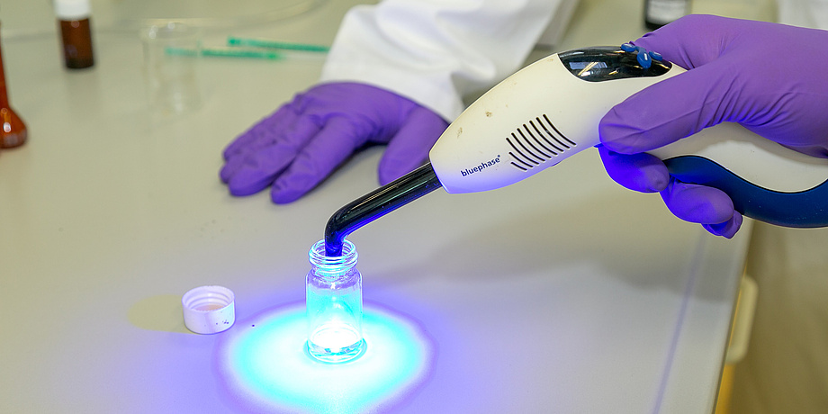 Close-up of hands in laboratory gloves with light source.