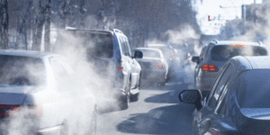 A street with a lot of cars and clouds of dust