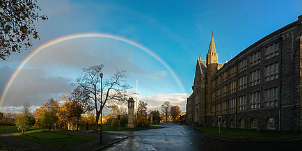 Wunderschönes altes Universitätsgebäude mit einem fantastischen Regenbogen, der das herbstliche Parkgelände am Campus der Norwegian University of Science and Technology (NTNU) überspannt.