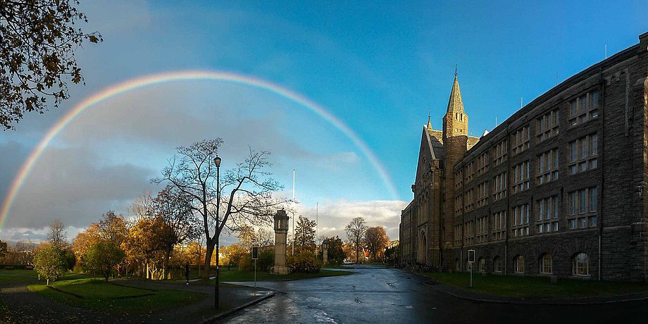 Wunderschönes altes Universitätsgebäude mit einem fantastischen Regenbogen, der das herbstliche Parkgelände am Campus der Norwegian University of Science and Technology (NTNU) überspannt.
