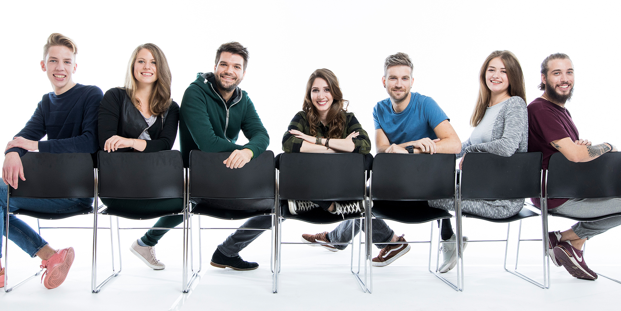 Sieben Studierende sitzen verkehrt auf Stühlen und blicken in die Kamera. Bildquelle: Kanizaj – TU Graz