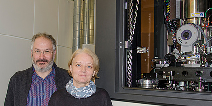 Forscher und Forscherin neben einem Elektronenmikroskop