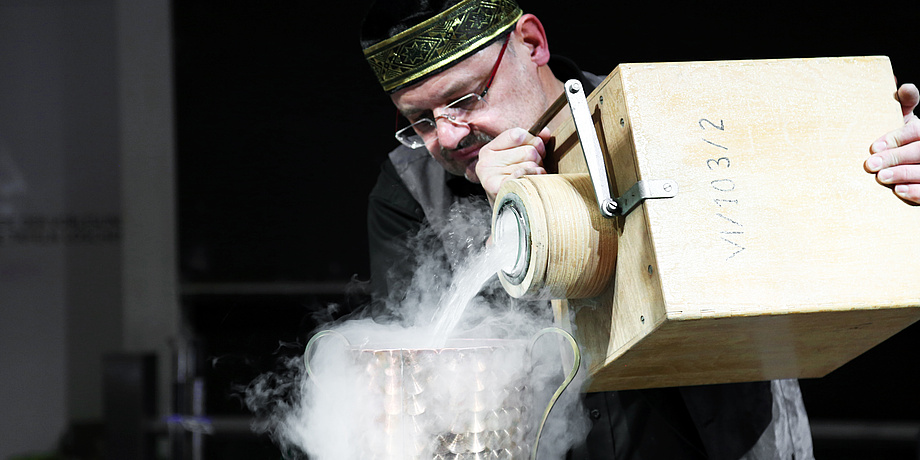 A man is holding a wooden box and is pouring steam out of it.