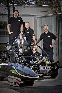 Four men with two vehicle prototypes.