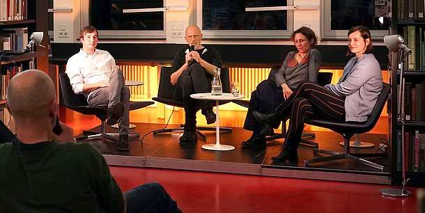Two women and two men are sitting on a stage in front of an audience.