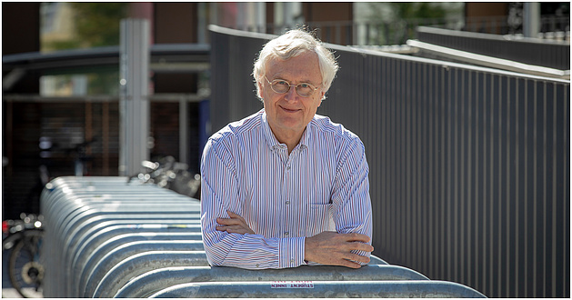 Man with glasses leans on metal balustrade