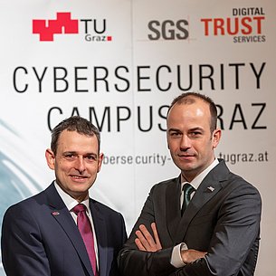 Two men in front of a Cybersecurity Campus Graz poster