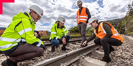 Two women and two men in high-visibility vests on a railroad track