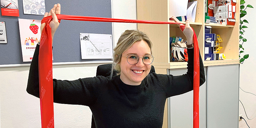 Woman with blond hair holds over head red tera ribbon.