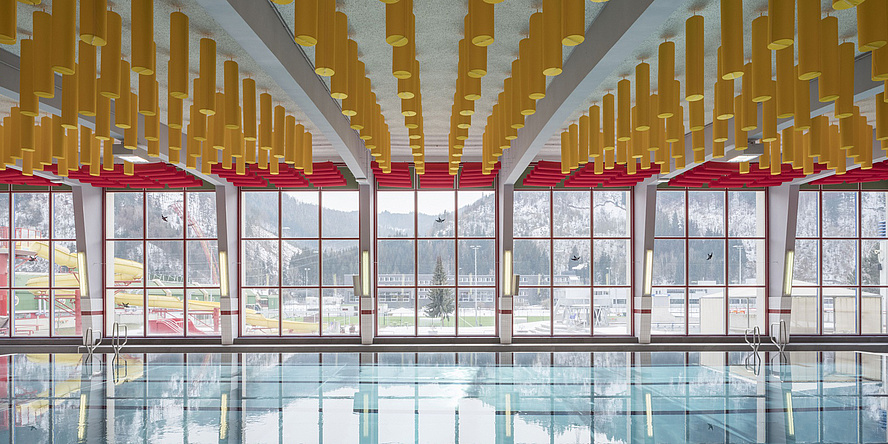 Hallenbad mit gelben Deckenelementen und großen Fenstern