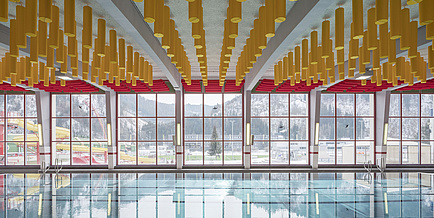 Hallenbad mit gelben Deckenelementen und großen Fenstern