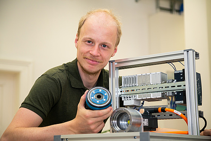 TU Graz researcher with small test bench and gearbox