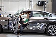 A woman sits in a car with the door open and looks at a laptop.