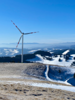 Verschneiter Berg mit Windrad.