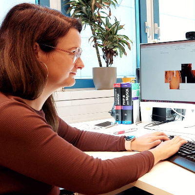 Eine Frau schreibt auf einem Keyboard am Computer.