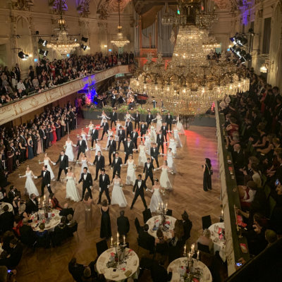 Männer und Frauen tanzen in einem Ballsaal.