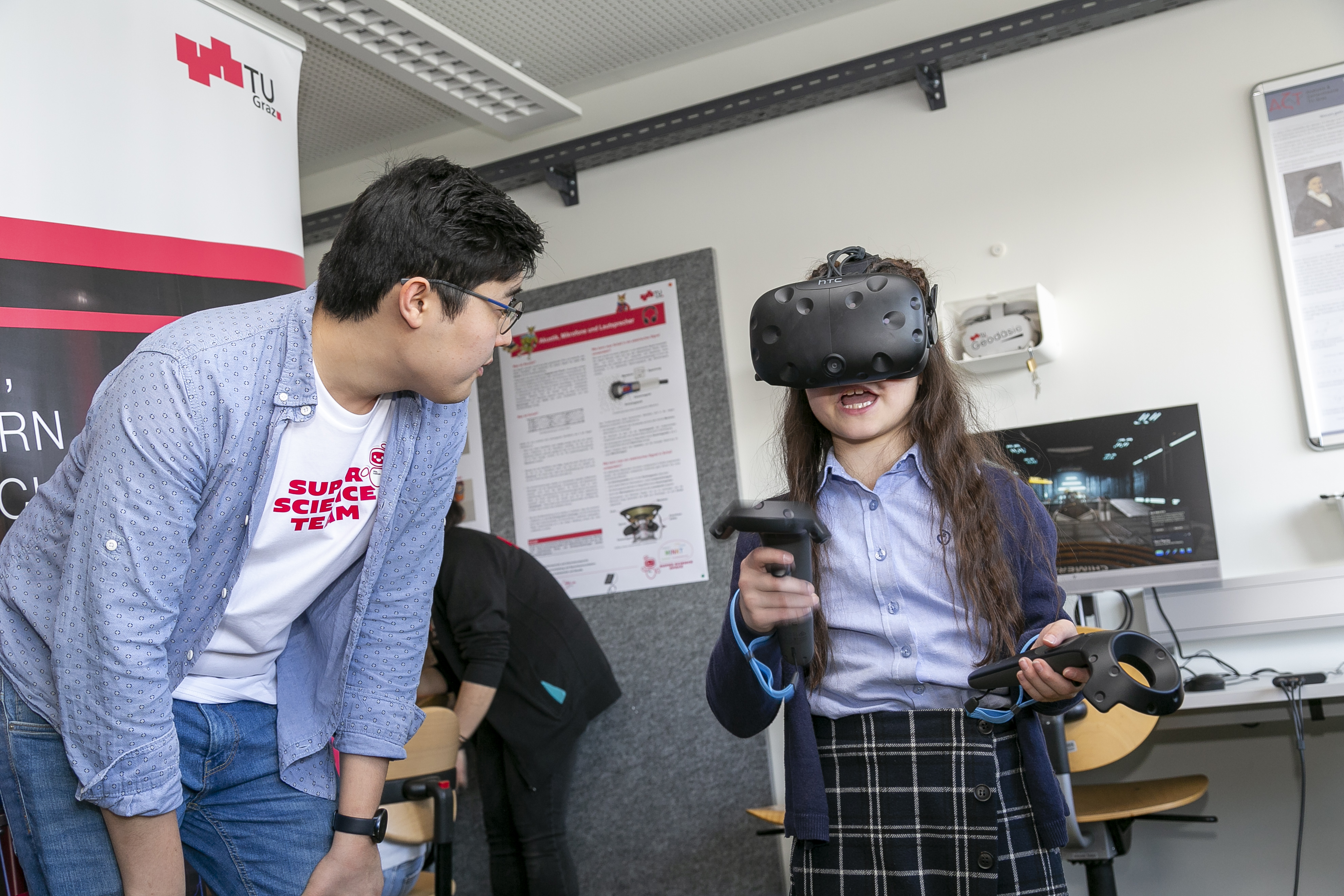 Ein Kind mit einer Virtual-Reality-Brille auf dem Kopf, daneben ein junger Erwachsener.