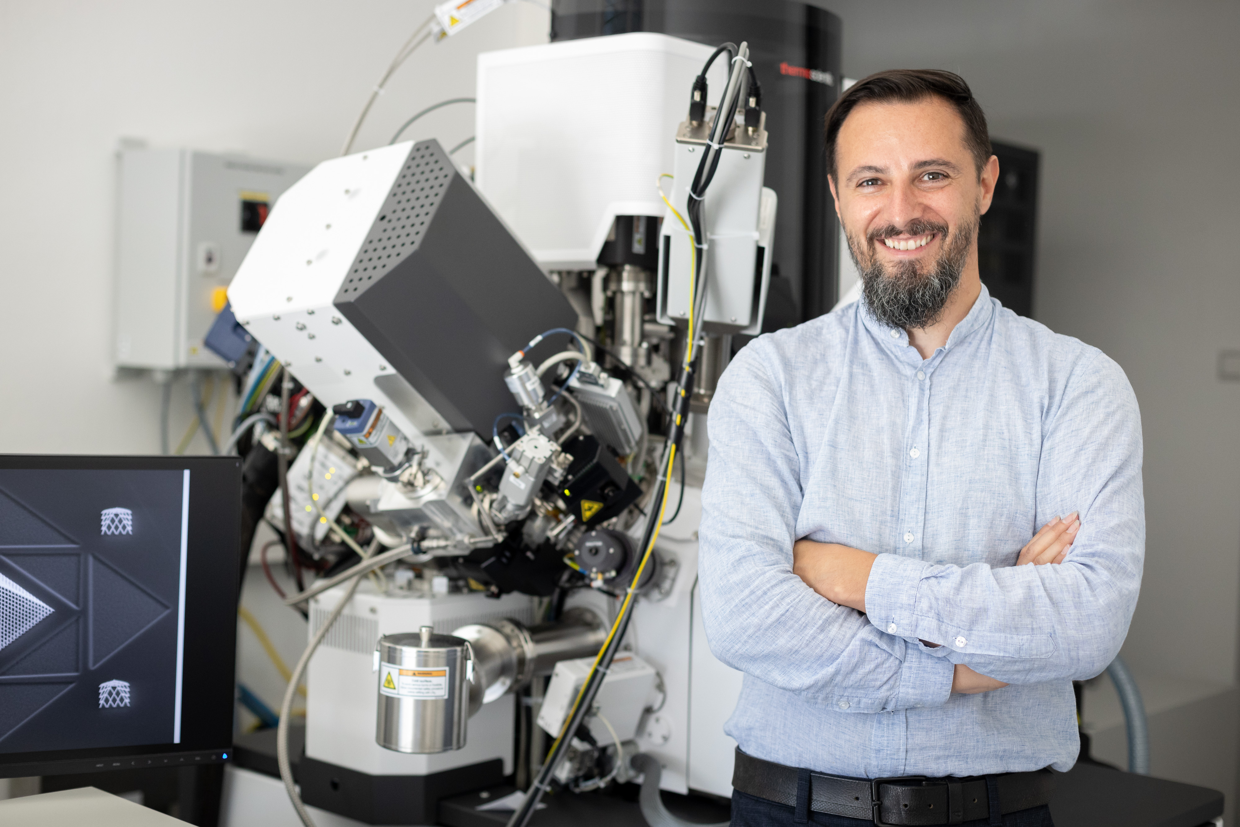 A man is standing next to a large microscope.