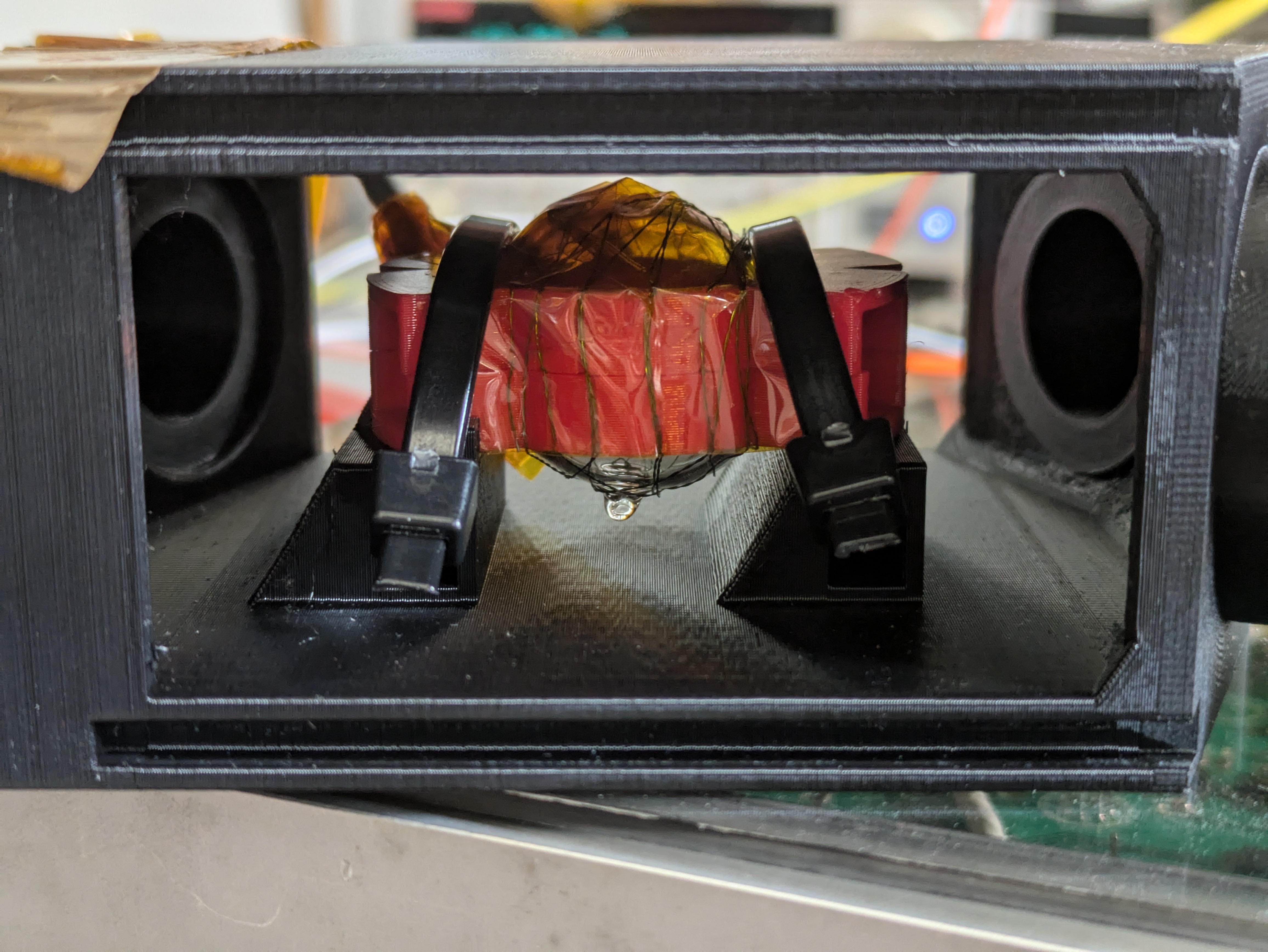 In einem offenen schwarzen Einbaurahmen steht eine rot verpackte Glaszelle.