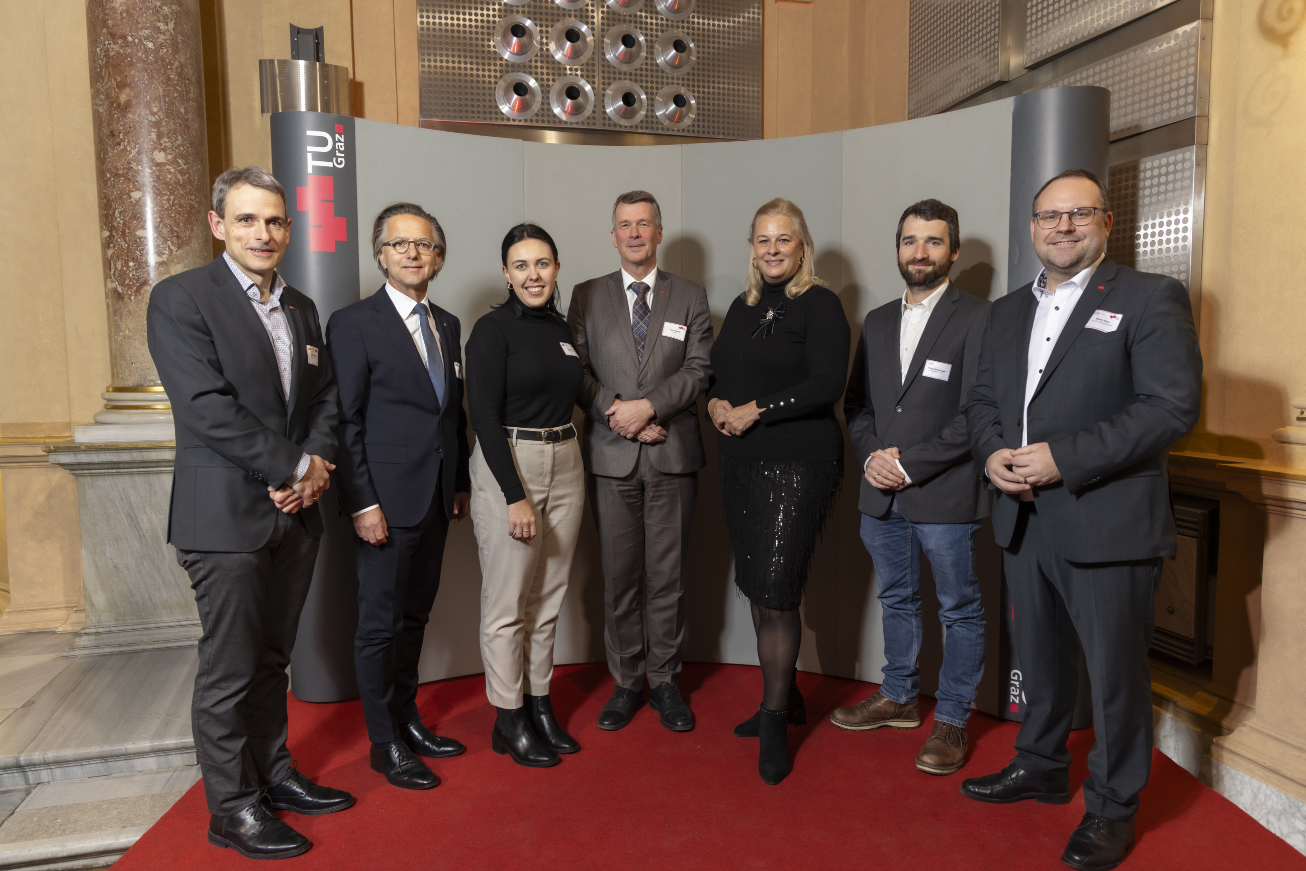 Seven people are standing next to each other, looking at the camera.