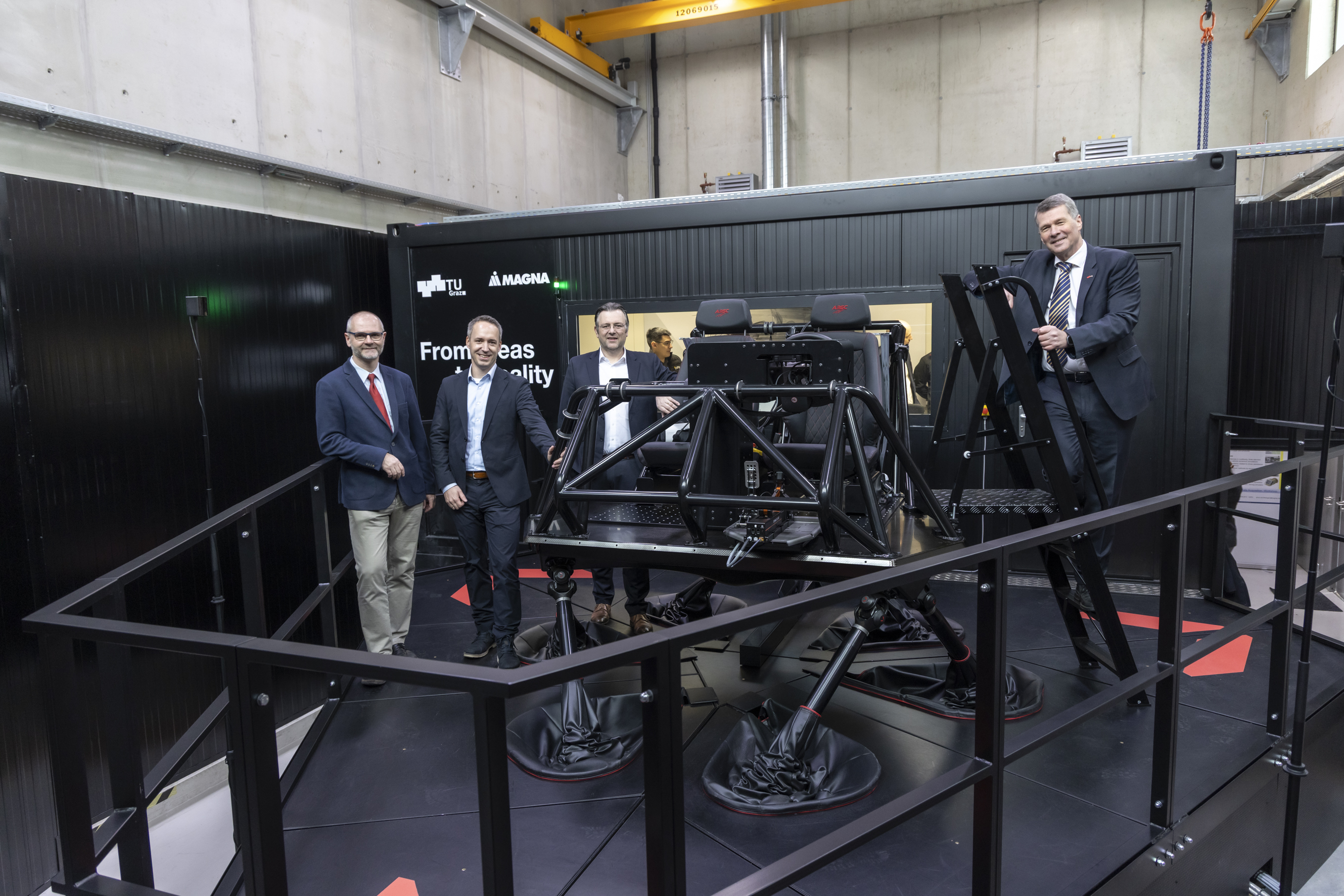 Four men pose for the camera in front of a cockpit standing on six stilts.