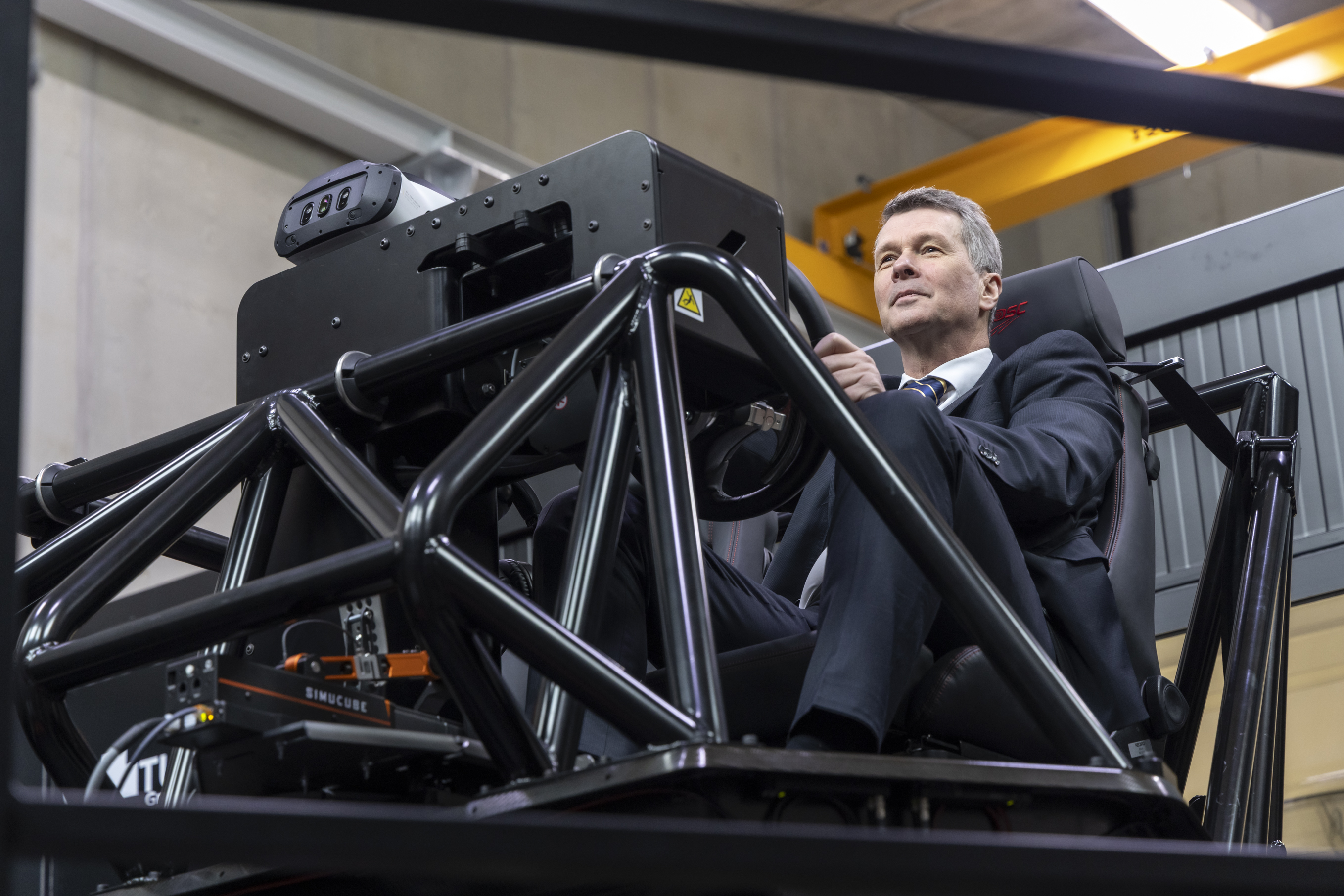 A man is sitting in a cockpit behind a steering wheel.