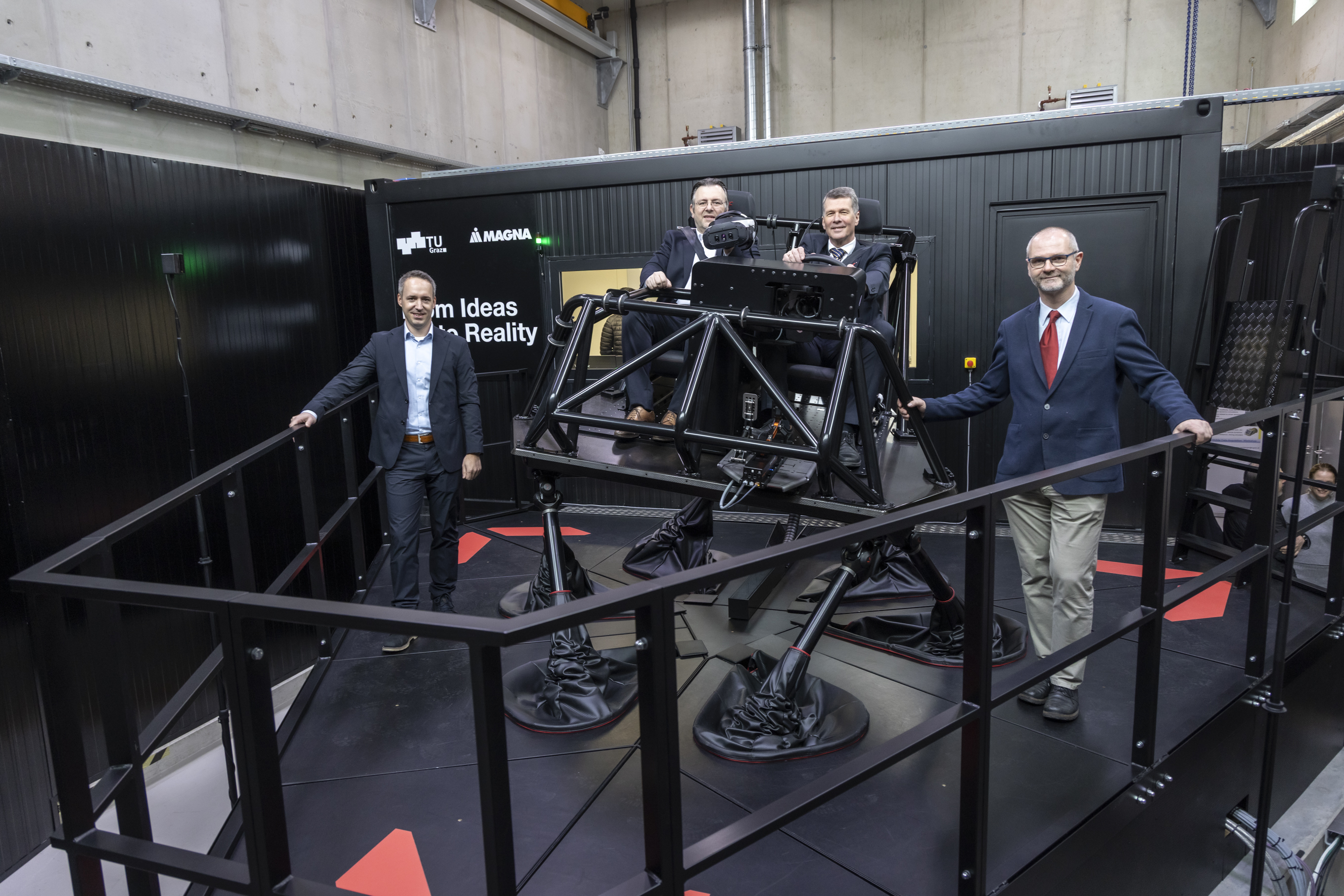 Four men pose for the camera in front of a cockpit standing on six stilts.