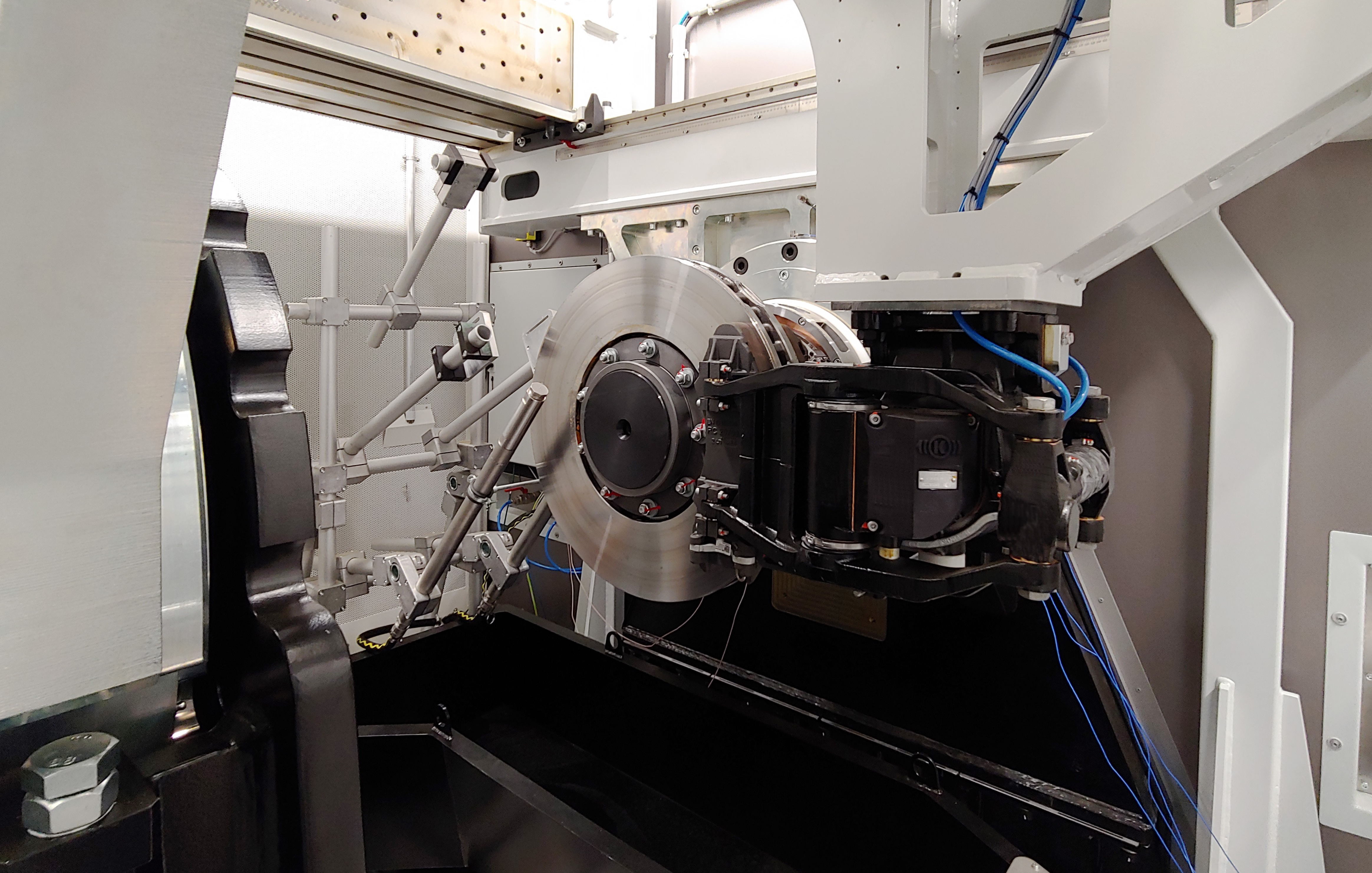 Ein weißer Raum, in dem eine Eisenbahnbremse an die Wand montiert ist, an der Sensoren und Bremsbacken befestigt sind.