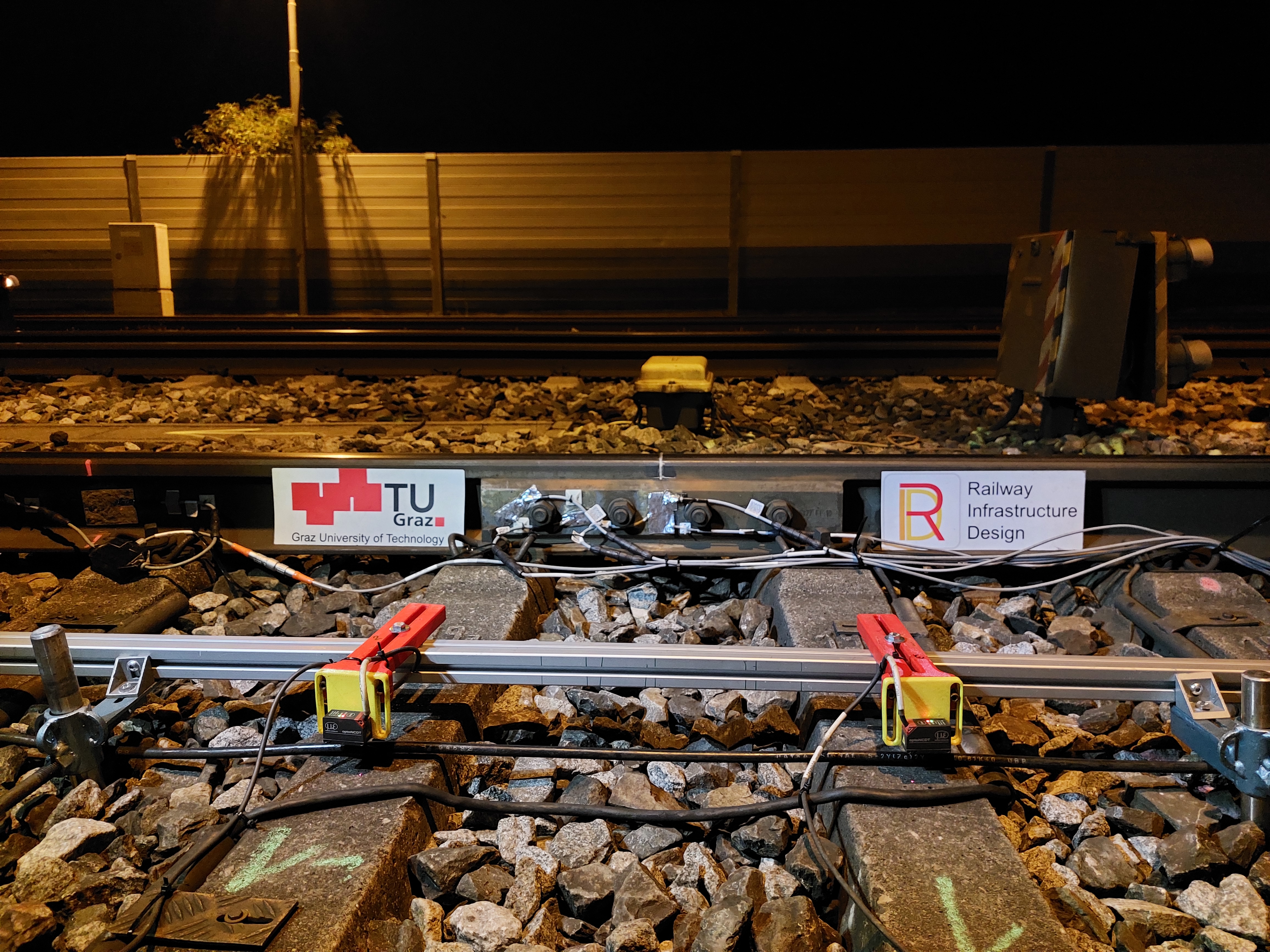 Ein Eisenbahngleis, an dem Messsensoren angebracht sind.