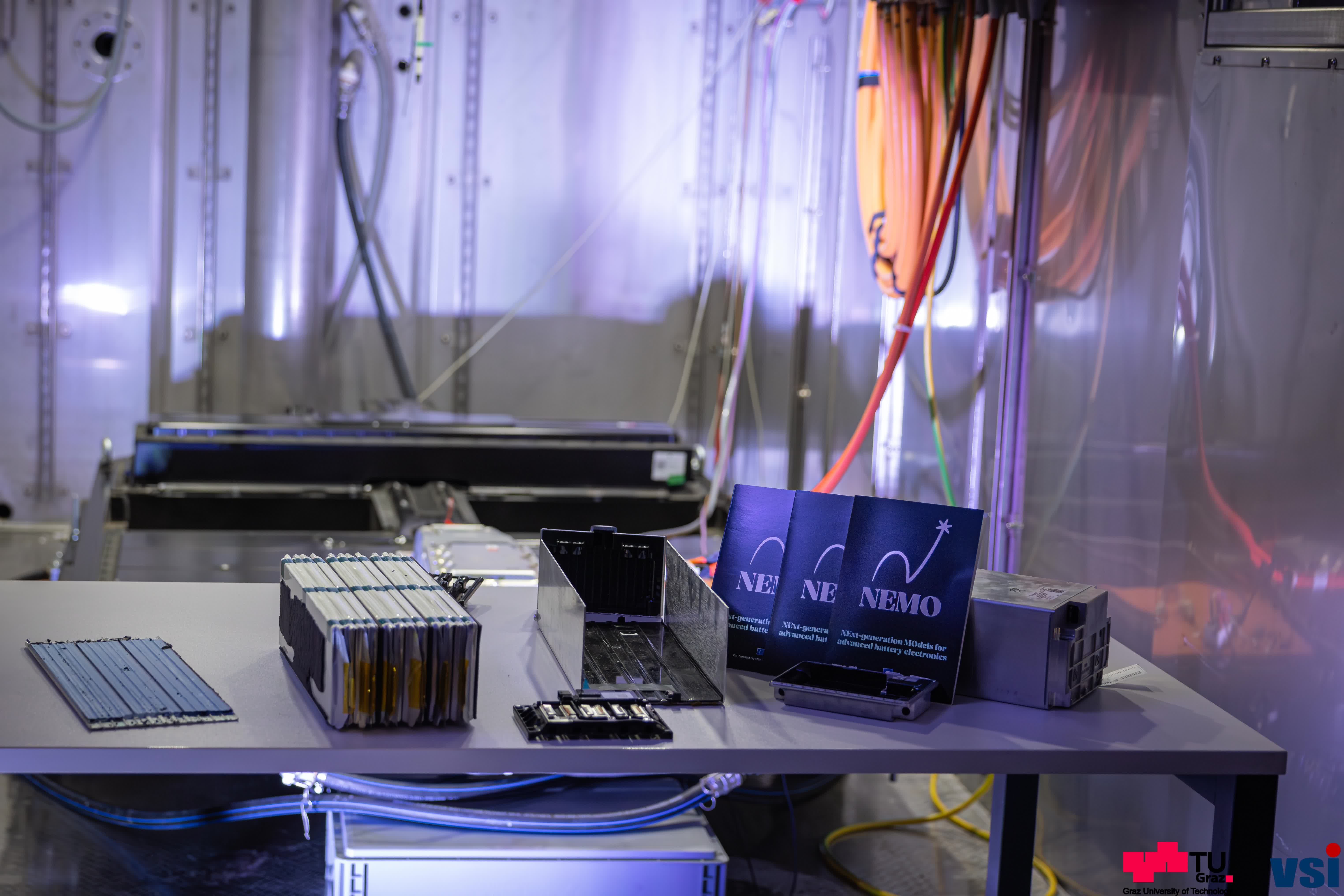An open battery pack for an electric car is sitting on a table. Next to it are small cards bearing the word ‘Nemo’.