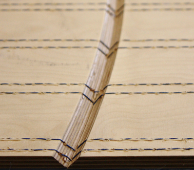 Ein von Nähten durchzogenes Stück Holz, in der Mitte befindet sich eine Falzrille.