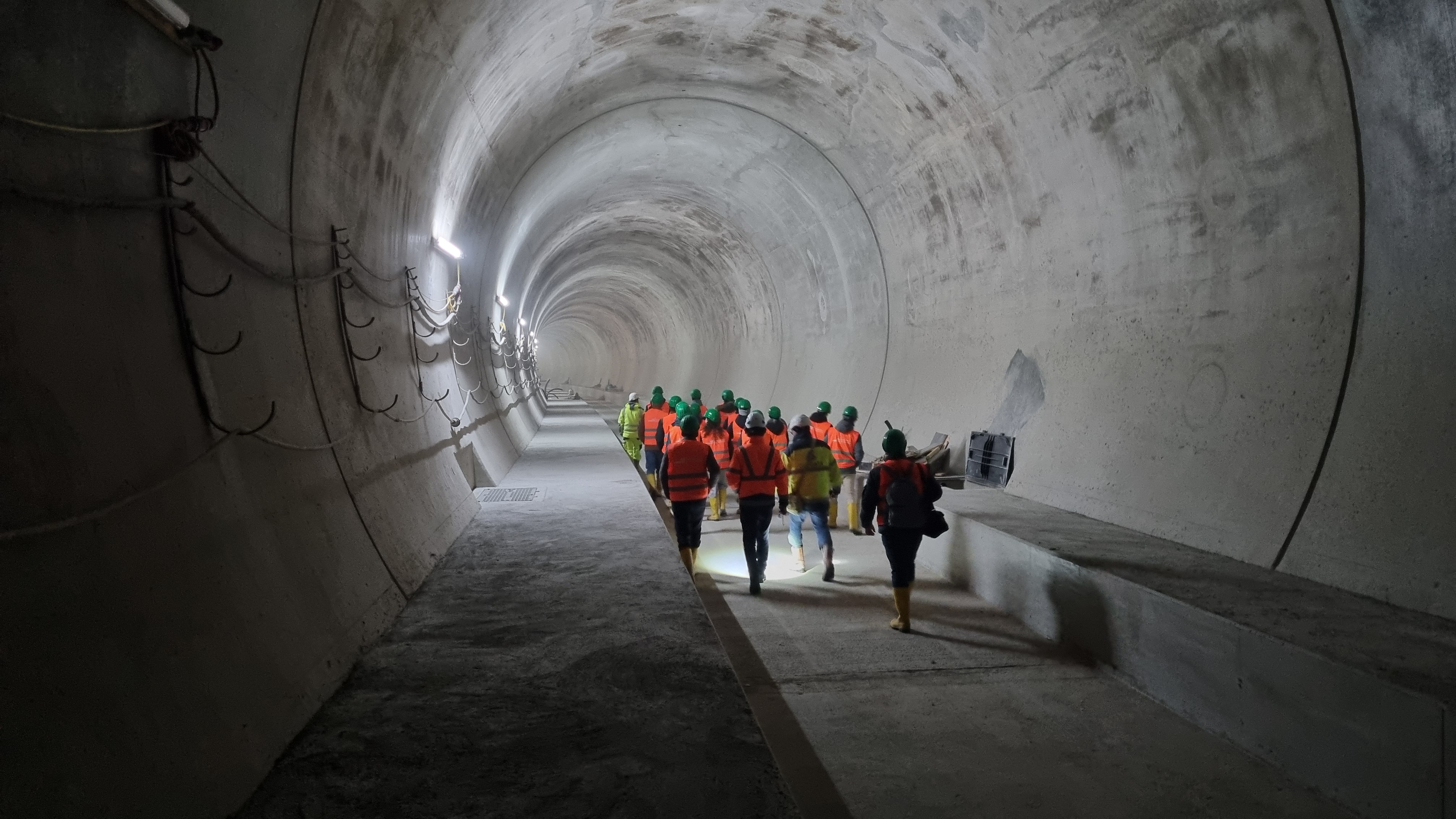 A group of people walk away from the camera through a tunnel tube.