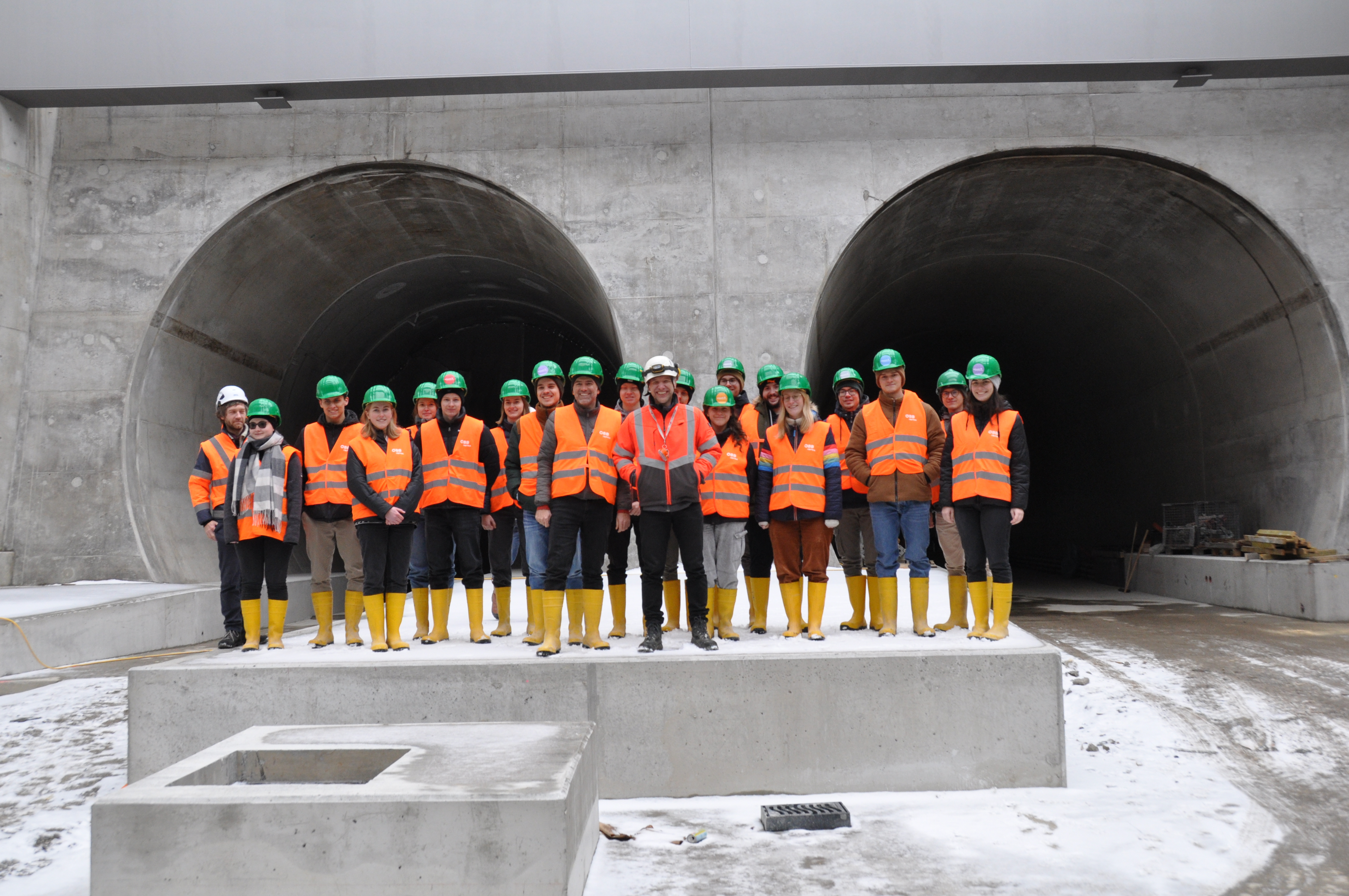 A group of people are standing in front of two tunnel openings.