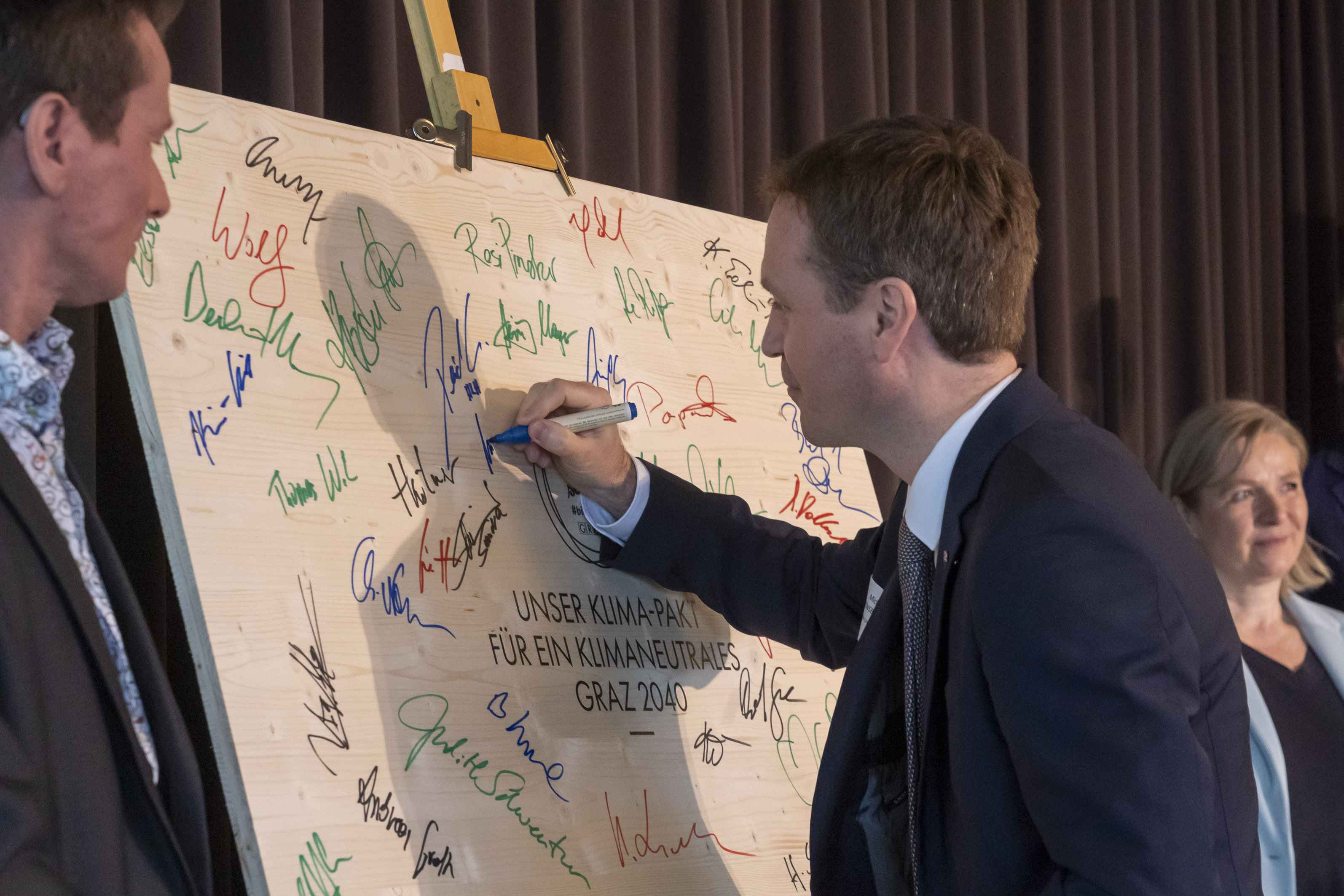 ein Mann unterschreibt mit einem Stift auf einer Tafel