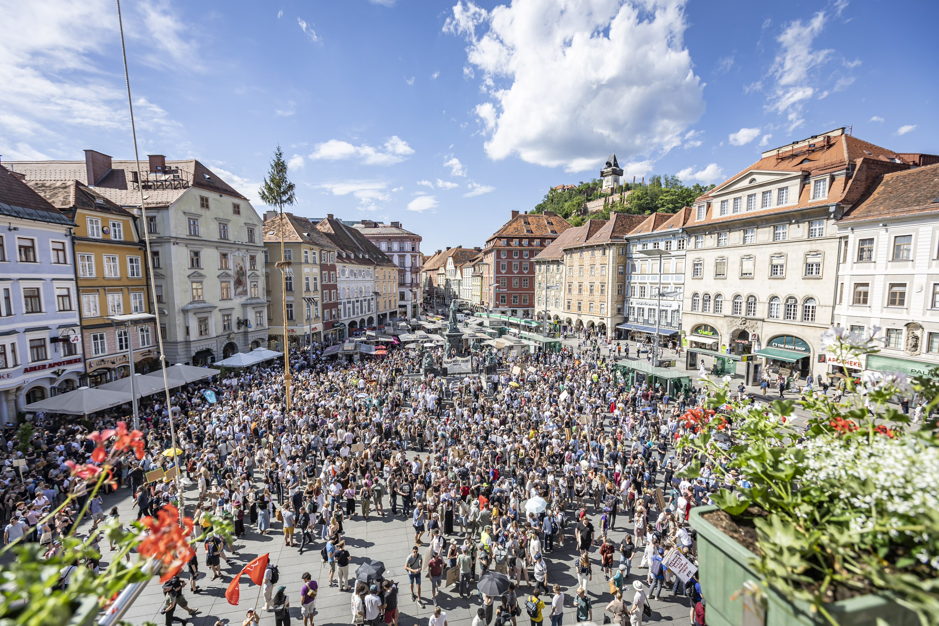 A large crowd is standing in a square around a column.